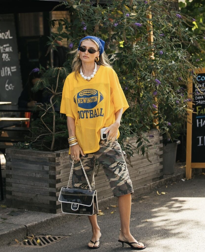 Mulher usando lenço azul como faixa no cabelo, suas roupas são estilo streetwear.