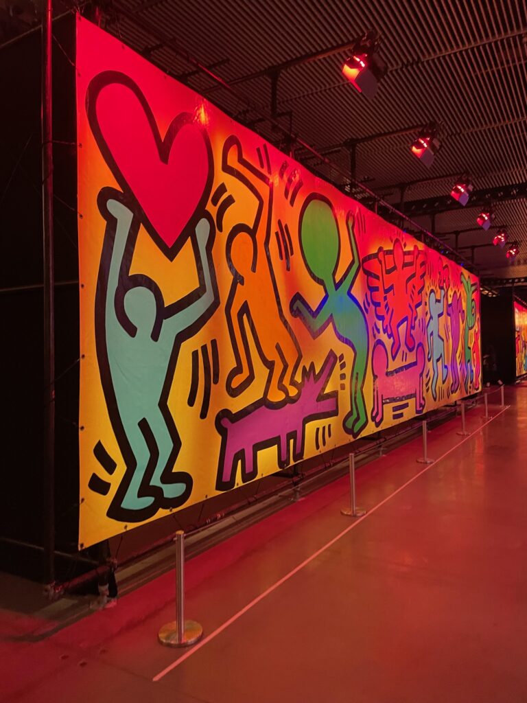 Foto de um mural de pictogramas coloridos na exposição Luna Luna: Forgotten Fantasy.