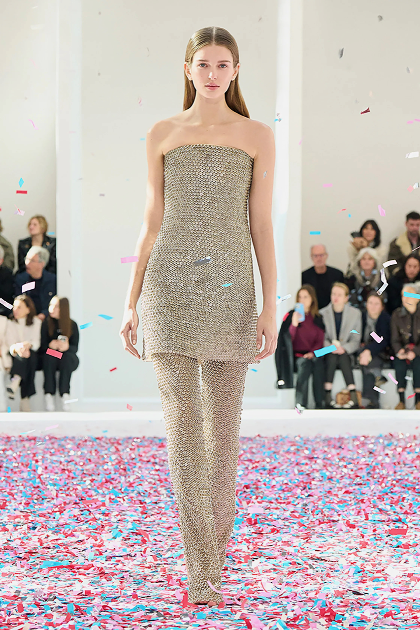 Roupa Courages sem alças. As peças são compostas por um vestido com ombros de fora por cima de uma calça de mesmo tecido prata.