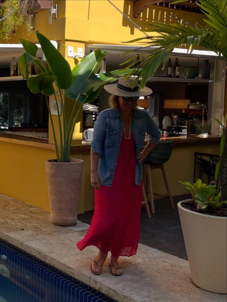 Foto da Silvia Scigliano com vestido longo, camisa jeans e chapeu de palha.