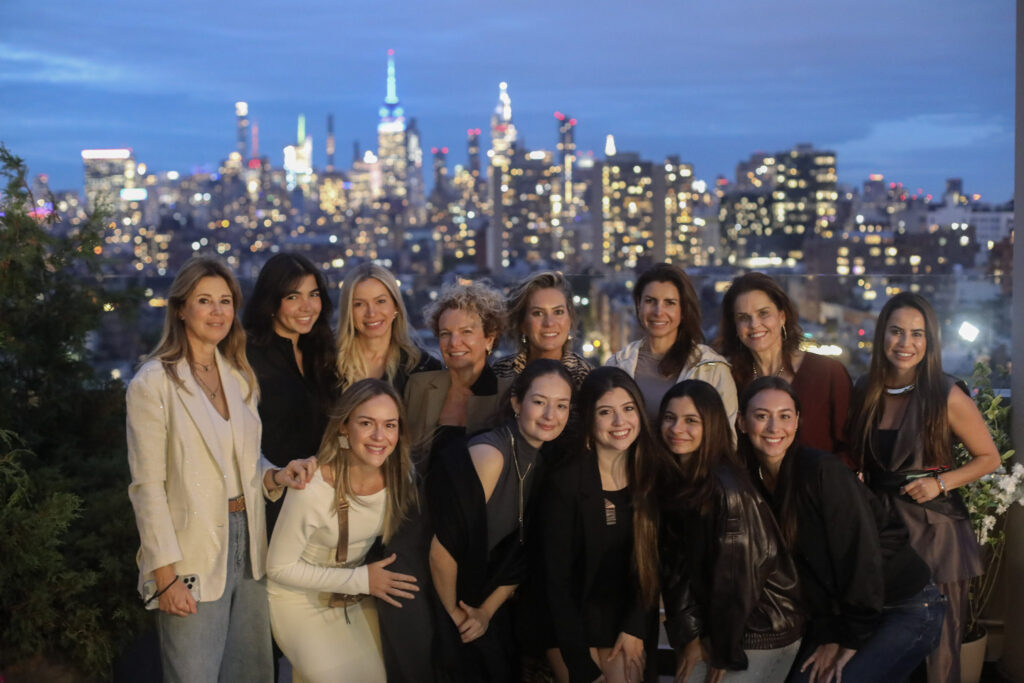 Foto do primeiro encontro do NY Fashion Tour, edição setembro de 2025. Na foto aparecem as aulas com as professoras do curso. Ao fundo vê-se as luzes e predios da cidade de Nova York.
