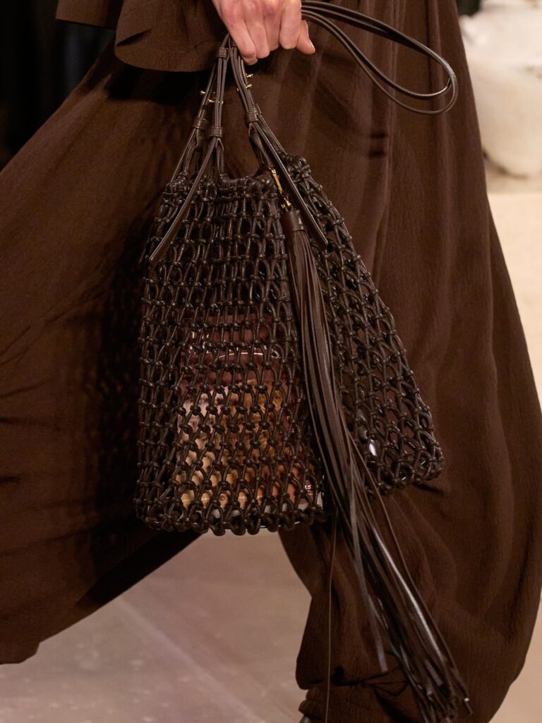 Foto de bolsa marrom  vazadacom epécie de cheveiro pendurado com franjas longas.