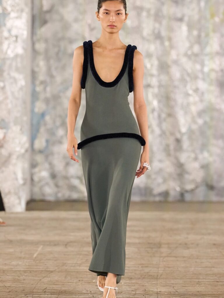 Modelo usa vestido longo cinza, com marcação baixa na cintura.